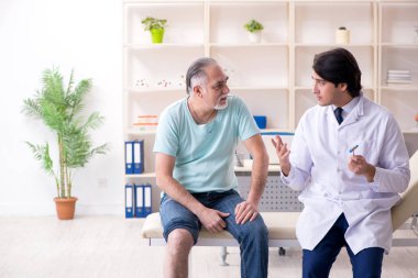 Yaşlı adam genç erkek doktoru ziyaret ediyor. 