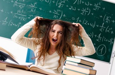 Karatahtanın önünde genç bayan matematik öğretmeni.  