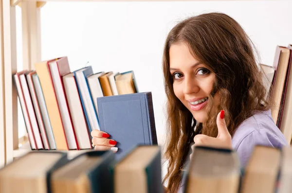 Ung kvinnlig student förbereder sig för tentamen på biblioteket — Stockfoto