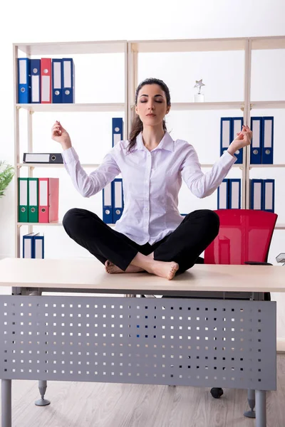 Young female employee doing exercises in the office