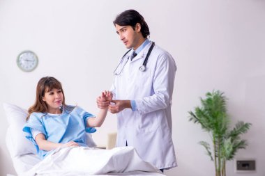 Erkek doktor koğuştaki kadın hastayı ziyaret ediyor. 