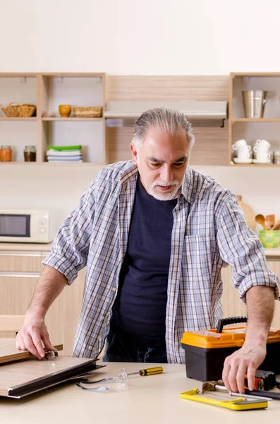 Betagter Lohnunternehmer, der in der Küche arbeitet — Stockfoto