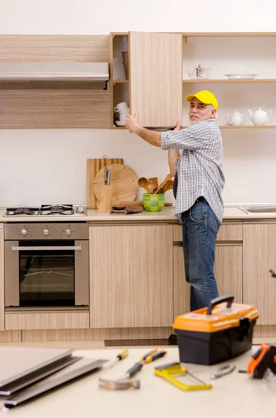 Contratista de edad reparador que trabaja en la cocina —  Fotos de Stock