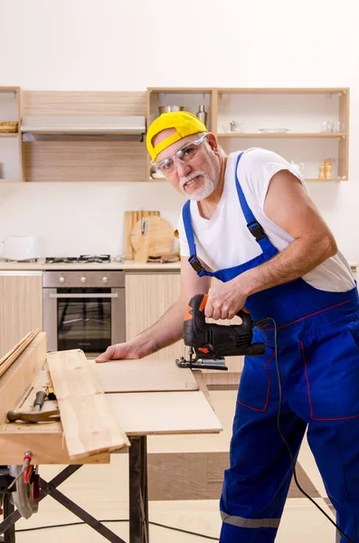 У віці підрядник ремонтант працює на кухні — стокове фото