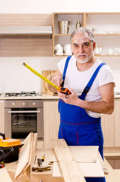 Reparador de empreiteiro envelhecido que trabalha na cozinha — Fotografia de Stock