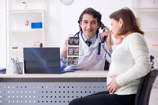 Vieja embarazada visitando joven médico masculino —  Fotos de Stock