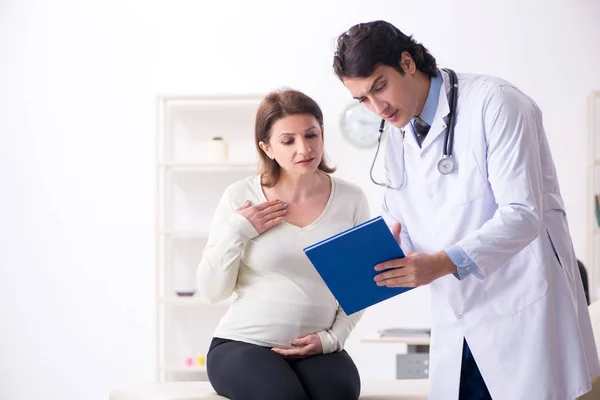 Vecchia donna incinta in visita giovane medico maschio — Foto Stock