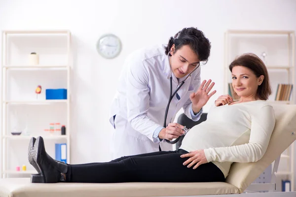 Velha mulher grávida visitando jovem médico masculino — Fotografia de Stock