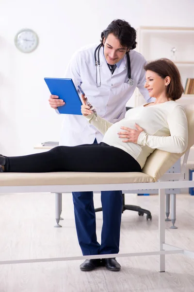 Old pregnant woman visiting young male doctor — Stock Photo, Image