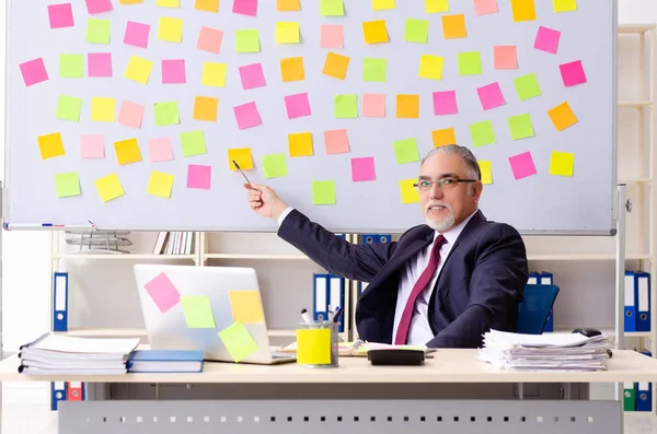 Leeftijd man werknemer in tegenstrijdige prioriteiten concept — Stockfoto