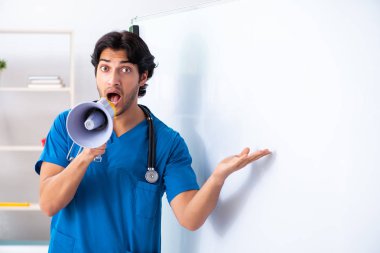 Genç erkek doktor beyaz tahtanın önünde. 