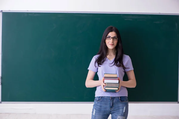 Genç bayan öğretmen yeşil panonun önünde. — Stok fotoğraf