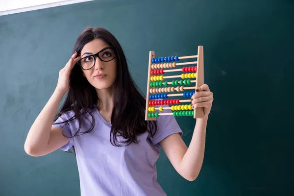 Fiatal tanárnő tanuló a zöld tábla előtt — Stock Fotó