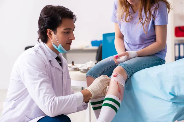 Erkek doktoru ziyaret eden bacağı yaralı genç bir kadın. — Stok fotoğraf