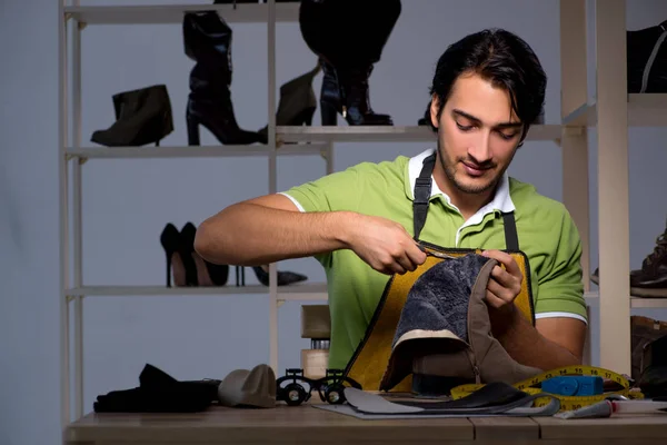 Jonge schoenmaker in workshop bij nacht — Stockfoto