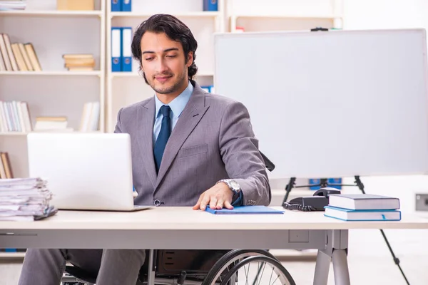 Jonge knappe werknemer in rolstoel op kantoor — Stockfoto