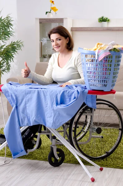 Nainen pyörätuolissa silitys kotona — kuvapankkivalokuva