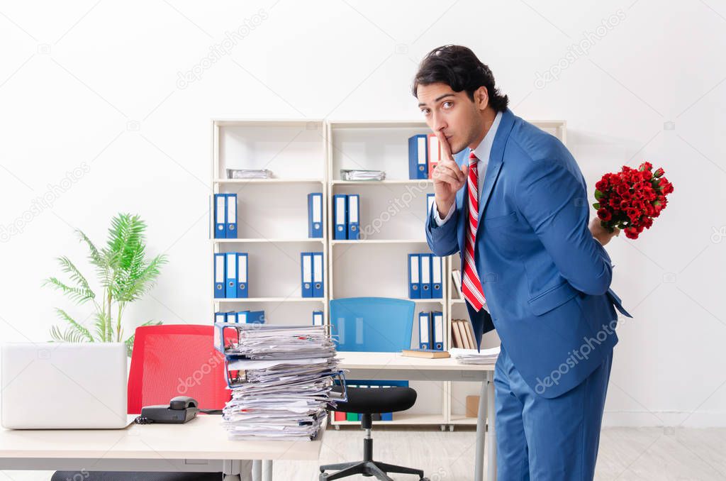Young male employee with bunch of flowers in the office 