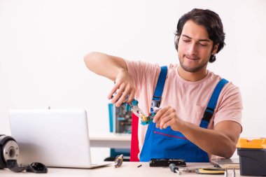 Genç bir erkek müteahhit bilgisayar tamir ediyor.  
