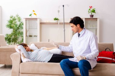 Genç, yakışıklı doktor hamile kadını ziyaret ediyor. 