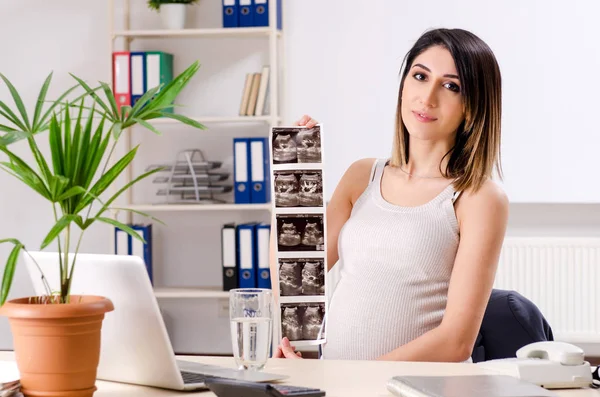 Jonge zwangere werkneemster op kantoor — Stockfoto