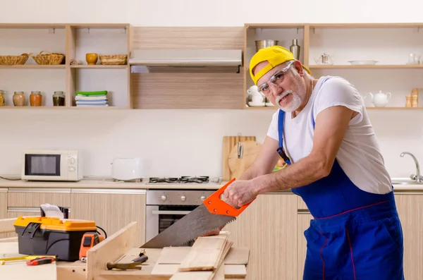Contratista de edad reparador que trabaja en la cocina —  Fotos de Stock