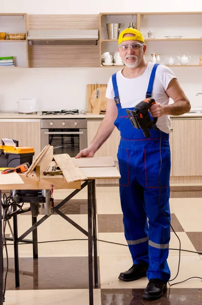 Betagter Lohnunternehmer, der in der Küche arbeitet — Stockfoto