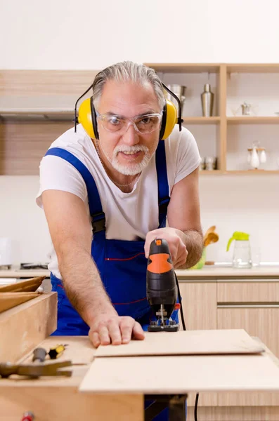 Reparador de empreiteiro envelhecido que trabalha na cozinha — Fotografia de Stock