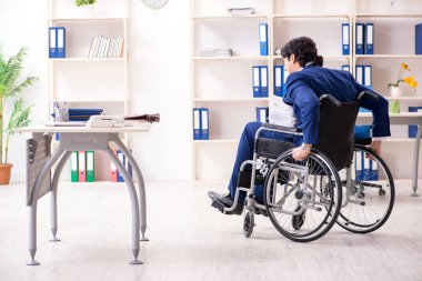 Ofiste çalışan tekerlekli sandalyede çalışan genç bir erkek. 
