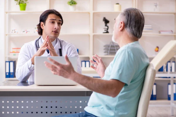 Old man visiting young male doctor — Stock Photo, Image