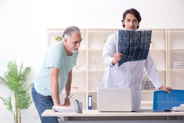 Old man visiting young male doctor — Stock Photo, Image
