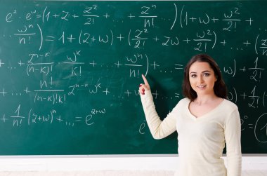 Karatahtanın önünde genç bayan matematik öğretmeni.  