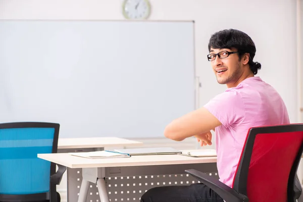 Jovem estudante do sexo masculino sentado na classe — Fotografia de Stock