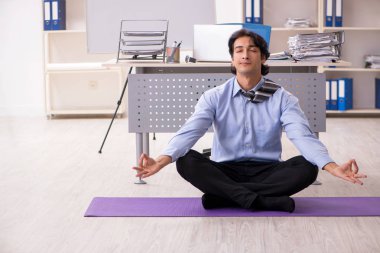 Genç yakışıklı erkek çalışanımız ofiste egzersiz yapıyor. 