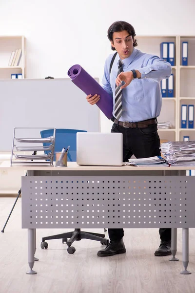 Young handsome male employee doing exercises in the office