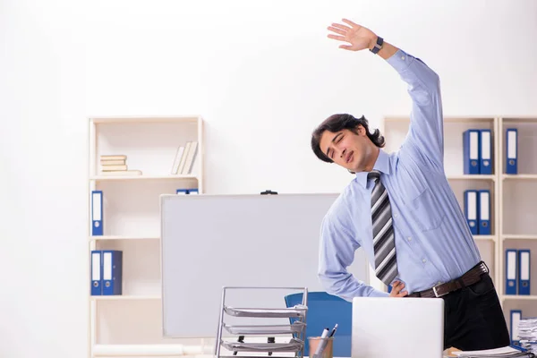 Junge hübsche männliche Angestellte machen Übungen im Büro — Stockfoto