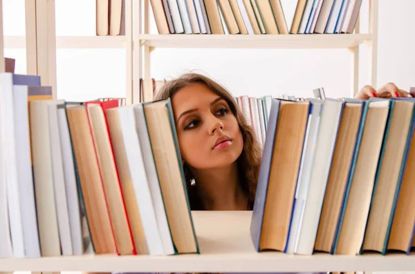 Ung kvinnlig student förbereder sig för tentamen på biblioteket — Stockfoto