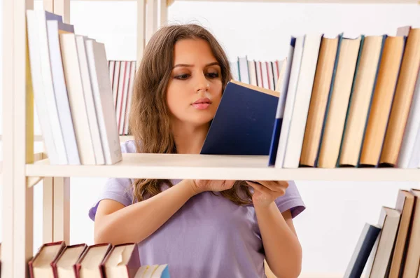 Jonge vrouwelijke student bereidt examens in de bibliotheek voor — Stockfoto