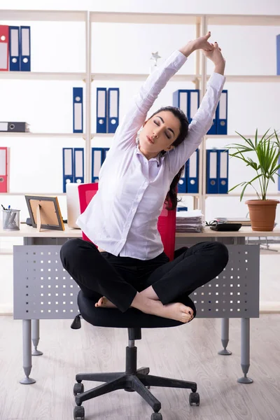 Joven empleada haciendo ejercicios en la oficina —  Fotos de Stock