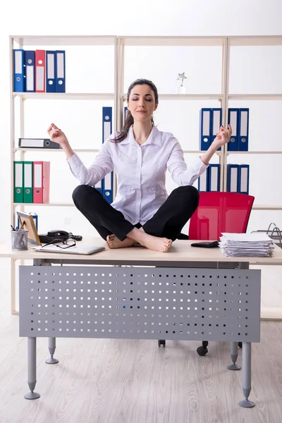 Joven empleada haciendo ejercicios en la oficina —  Fotos de Stock