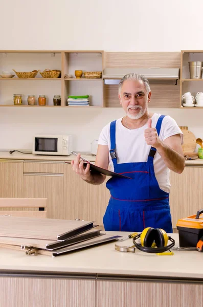 Reparador de empreiteiro envelhecido que trabalha na cozinha — Fotografia de Stock