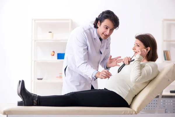Vieja embarazada visitando joven médico masculino — Foto de Stock