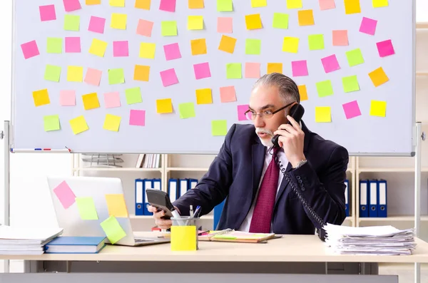 Hombre de edad empleado en el concepto de prioridades contradictorias — Foto de Stock