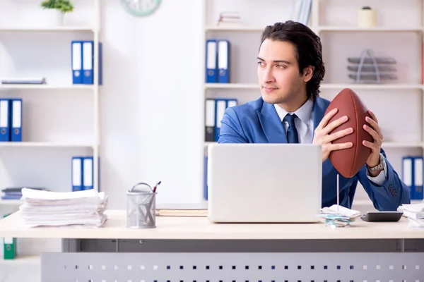 Молодой привлекательный бизнесмен с мячом для регби в офисе — стоковое фото