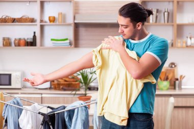 Genç adam evde çamaşır ütülüyor. 