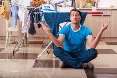 Genç adam evde çamaşır ütülüyor. 