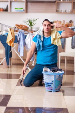 Genç adam evde çamaşır ütülüyor. 