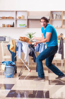 Genç adam evde çamaşır ütülüyor. 