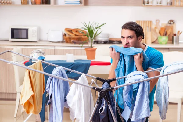 Jovem marido fazendo roupas de engomar em casa — Fotografia de Stock