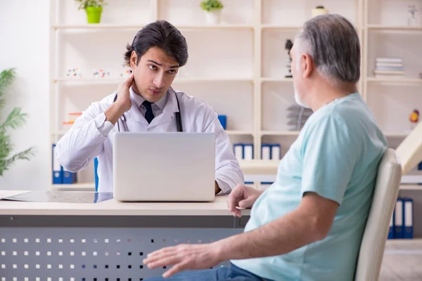 Old man visiting young male doctor — Stock Photo, Image